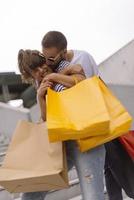 Portrait of cheerful Caucasian young couple man and woman holding many paper bags after shopping while walking and talking on street. Happy family couple with packages outdoor. Buying concept photo