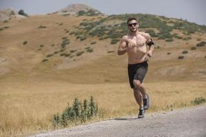 corredor de hombre deportivo corriendo en la meseta de la montaña en verano foto