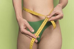 chica mide sus volúmenes con una cinta métrica. cuerpo sano y hermoso. cuerpo femenino, cintura delgada foto