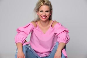 Portrait of beautiful young woman in cute pink shirt and blue jeans posing in studio. Concept of beauty, emotions, facial expression, lifestyle, fashion, youth culture photo