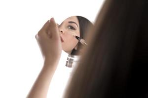 Portrait of a young woman applying liquid make up on her face. Isolated on white background photo