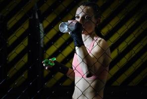 female fighter drinking water and resting after the training. photo