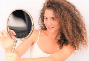 young woman in front of the mirror checking her face skin photo