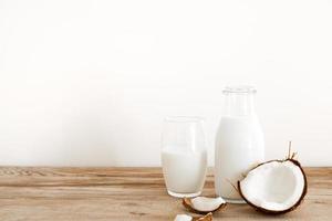 leche de coco fresca en botella de vidrio, bebida saludable vegana no láctea. mesa de madera, primer plano. espacio libre para texto, espacio de copia. foto