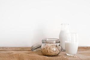 Fresh oat milk in glass bottle, vegan non dairy healthy drink. Wooden table, close-up. Free space for text, copy space. photo