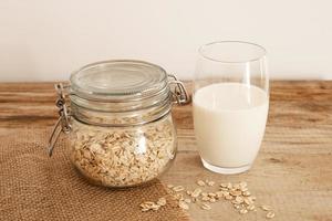 Fresh oat milk in glass, vegan non dairy healthy drink. Wooden table, close-up. Alternative product, lactose free, natural ingredients. Healthcare, lactose intolerance. photo