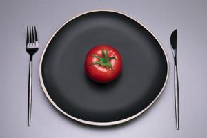 Tomato on the black plate. The concept of diet. photo