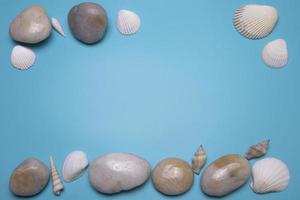 conchas marinas y pequeñas piedras sobre el fondo azul, con espacio libre para texto. foto