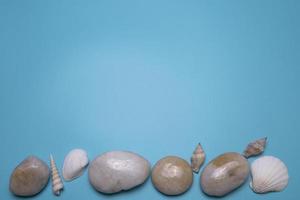 conchas marinas y pequeñas piedras sobre el fondo azul, con espacio libre para texto. foto