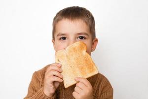 Children and gluten. Preschool boy with toasted bread. Gluten intolerance by kids. Copy space on bread for text or symbol. photo