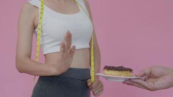 dieta e dieta. corpo feminino magro de beleza confunde rosquinha. mulher em roupas de ginástica atinge meta de perda de peso para uma vida saudável, louca por magreza, cintura fina, nutricionista. video