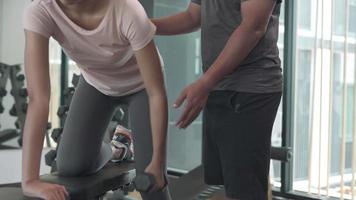 frau trainiert mit hantel und hat unterstützungsaktivitäten durch trainer. Fitnesstraining wird empfohlen, um richtig zu trainieren, um das Verletzungsrisiko für Ihre Muskeln zu verringern. Fitness-Konzept. video