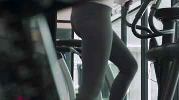 woman exercisers in fitness for calories burned and reduce weight. A woman diet by exercising on elliptical machine . Fitness and diet concept. video