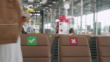 New normal concept. Asian women wear a mask and sit between chairs to reduce the spread of the coronavirus. Tourists wait to get on planes during the covid-19 outbreak. video