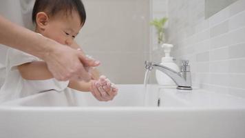 madre ayuda a su hija a lavarse las manos después de manipular un objeto para prevenir la infección por el virus. lavarse las manos con frecuencia desechar el virus. concepto de higiene personal. video