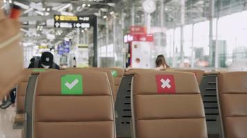 New normal concept. Asian women wear a mask and sit between chairs to reduce the spread of the coronavirus. Tourists wait to get on planes during the covid-19 outbreak. video