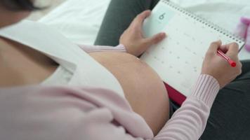 une femme enceinte fait une marque sur la date prévue de l'accouchement. la césarienne est un moyen pour les femmes enceintes de connaître une date d'accouchement. concept dû à l'accouchement. video