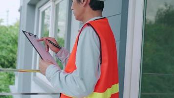 inspector o ingeniero está inspeccionando e inspeccionando un edificio o casa usando una lista de verificación. ingenieros y arquitectos o contratistas trabajan para construir la casa antes de entregársela al propietario. video