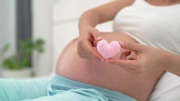 la femme enceinte montre un mini coeur rose pour l'amour de l'enfant à naître. le cœur rose représente les sentiments d'une femme pour l'importance de l'enfant. concept de relation mère-bébé. video