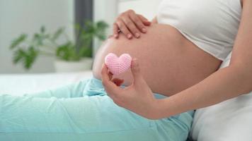 The pregnant woman show mini heart pink for love to the unborn child. The pink heart represents a woman's feelings for the importance of the child. Mother-baby relationship concept. video