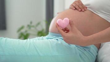la femme enceinte montre un mini coeur rose pour l'amour de l'enfant à naître. le cœur rose représente les sentiments d'une femme pour l'importance de l'enfant. concept de relation mère-bébé. video