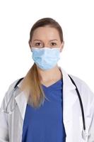 Portrait of young female doctor in medical mask looking at camera, isolated on white background. Medicine, healthcare during Covid-19. Doctor with white coat, stethoscope over neck, ready help patient photo