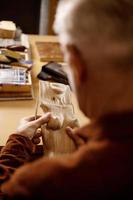 Artist is grinding wooden sculpture. Carpenter working with wood in workshop. Man and his hobby. Closeup view, only hands in frame. photo