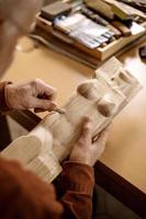 Artist is grinding wooden sculpture. Carpenter working with wood in workshop. Man and his hobby. Closeup view, only hands in frame. photo