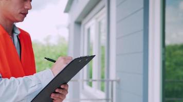 un inspecteur ou un ingénieur inspecte et inspecte un bâtiment ou une maison à l'aide d'une liste de contrôle. ingénieurs et architectes ou entrepreneur travaillent pour construire la maison avant de la remettre au propriétaire. video