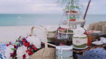 cesta de piquenique com comida e suco de coco na praia. céu limpo e praias de areia branca com o som das ondas e vista para o mar. conceito relaxe e viaje na província de samui. video