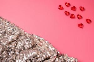 Pink Valentine's Day background with hearts and shiny, glittering fabric with sequins. Free space for text, copy space. Postcard, greeting card design. Love, celebration concept. photo