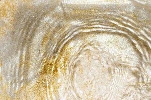 Golden and silver sparkles in water. Glitter and liquid texture. Abstract background with golden an silver particles. Shining celebration background. Festive backdrop for your projects.