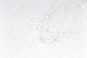 superficie de agua blanca, transparente y clara con salpicaduras y pequeñas burbujas. textura de agua vista de cerca fondo de naturaleza abstracta de moda. foto