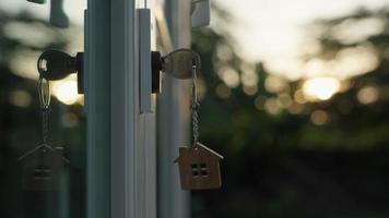 Landlord house key for unlocking a house is plugged into the door. Second hand house for rent and sale. keychain is blowing in the wind. Landlord for new house, rent , sale, renovate, investment. video