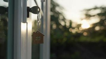 la clé de la maison du propriétaire pour déverrouiller une maison est branchée sur la porte. maison d'occasion à louer et à vendre. porte-clés souffle dans le vent. propriétaire pour maison neuve, location, vente, rénovation, investissement. video