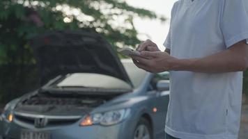 man använda sig av mobil telefon ring upp till försäkring på grund av till olycka bil genom en mobil Ansökan system.man sökningar för en garage till ha hans bil repareras under en lantlig Turné. bil försäkring begrepp. video