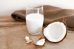 Fresh coconut milk in glass, vegan non dairy healthy drink. Wooden table, close-up. photo