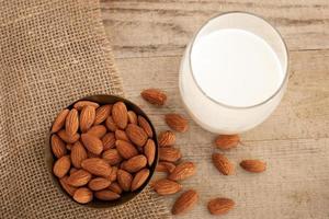 Fresh almond milk in glass, vegan non dairy healthy drink. Wooden table, close-up. Alternative product, lactose free, natural ingredients. Healthcare, lactose intolerance. photo