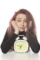 worried young woman holding alarm clock in her hand photo