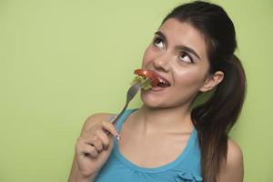 retrato de una chica juguetona feliz comiendo ensalada fresca de un bol foto