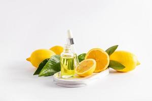 cosmetic lemon oil, whey with vitamin C, in an open bottle with a pipette filled with cosmetics. ripe lemons, white background. photo