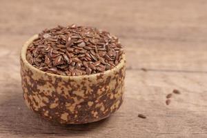 flax seeds in a wooden bowl on a wooden background, top view photo
