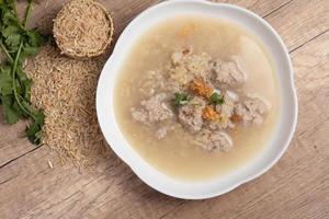 papilla de arroz integral jazmín con carne de cerdo sobre fondo de madera.espacio de copia de alimentos saludables foto