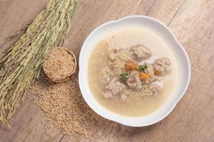 Jasmine brown rice porridge with pork on wooden background.Healthy food copy space photo