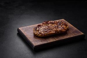 Delicious juicy grilled pork steak with spices and herbs photo