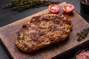 Delicious juicy grilled pork steak with spices and herbs photo