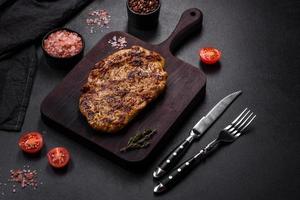 Delicious juicy grilled pork steak with spices and herbs photo