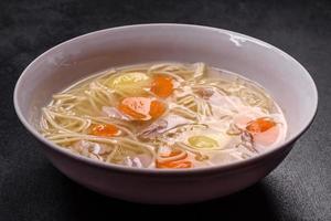 Delicious soup with noodles, chicken and carrots with spices and herbs photo