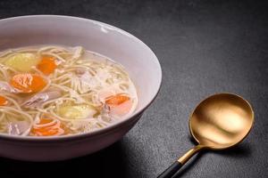 Delicious soup with noodles, chicken and carrots with spices and herbs photo