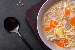 Delicious soup with noodles, chicken and carrots with spices and herbs photo
